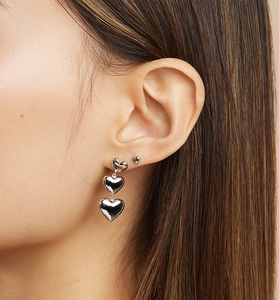Close-up of triple heart drop earrings in polished silver with minimalist stud style