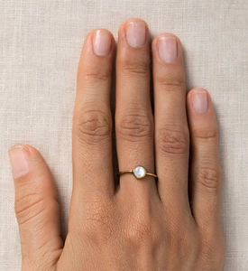 Detail of elegant gold-plated silver ring with white mother of pearl inlay on finger