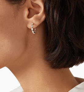 Close-up of rose gold huggie hoop earring with pear-cut cubic zirconia on model ear