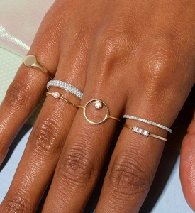 Close-up of stacked gold and silver S925 rings with pave diamonds and small pearl on finger