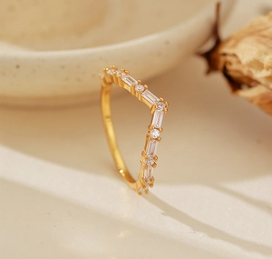 Vue latérale macro d'une bague dorée en V sertie de zircons ronds et baguettes polis