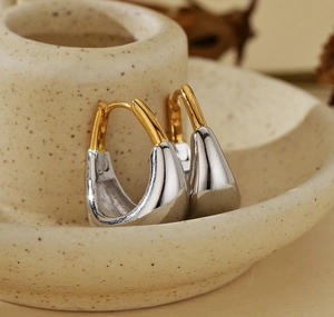 Vue macro de boucles d'oreilles bicolores en forme de U sur un plateau en céramique