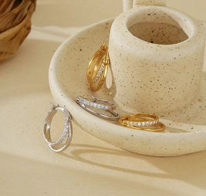 Detail of interlocking double hoop earrings in gold and silver with zircon micro-pave
