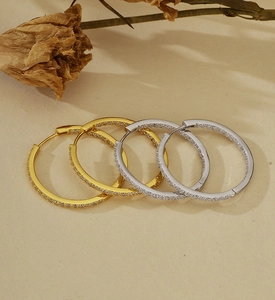 Detailed view of silver and gold hoop earrings with sparkling cubic zirconia inlay