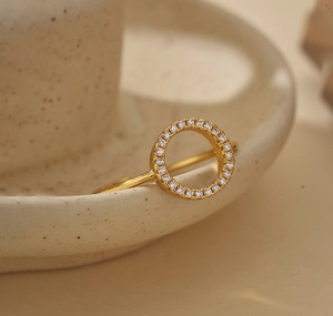 Macro d'une bague circulaire creuse dorée sertie de zircons blancs sur céramique