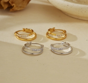 Detailed macro view of double-layer silver earrings with gold plating and zircon micro-paving