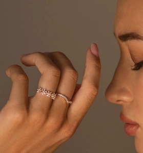 Détail macro d'une bague fleur en or avec zircons et diamants pavés sur un doigt