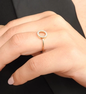 Détail d'une bague ouverte dorée avec forme en O creuse et pavage de pierres en zircone