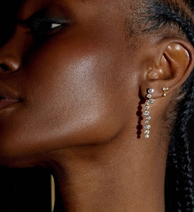 Close-up of dangling zircon drop earrings and floral stud on model with dark skin tone