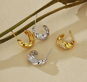 Macro detail of twisted 925 silver earrings with pavé zircon in gold and silver finish