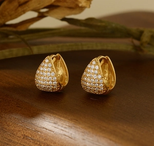 Macro detail of S925 sterling silver stamp on gold triangular micro-pave hoop earrings