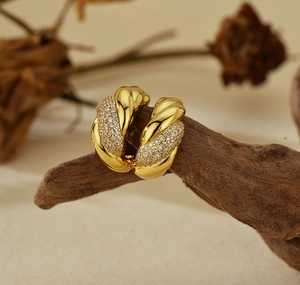 Detail of gold twisted earrings with pave-set zirconias on a natural wood branch