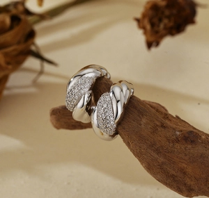 Macro shot of silver twisted hoop earrings with micro-pave cubic zirconia on wood