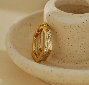 Macro shot of gold-plated hexagonal silver earrings with pavé zircons on a ceramic edge