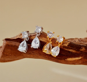 Gros plan de boucles d'oreilles goutte argentées et dorées avec cristaux sur bois