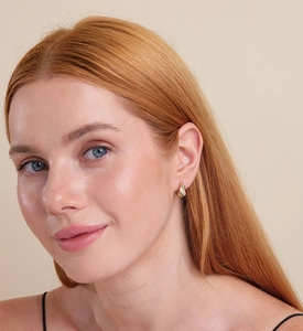 Close-up of elegant gold twisted hoop earrings with micro-inlaid zircons on model ear