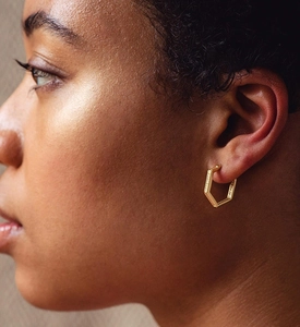 Detail of gold S925 silver hexagonal hoop earring with pavé zircon on model ear