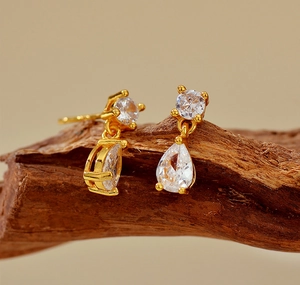 Détail macro de boucles d'oreilles goutte dorées avec zircons étincelants sur bois rustique