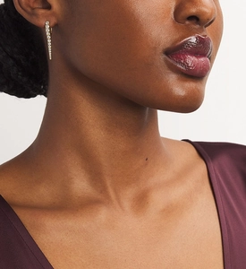 Close-up of gold cone drop earrings with micro-pave diamonds on a model's ear