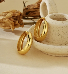 Detailed close-up of chunky gold hoop earrings with S925 hallmark on inner band