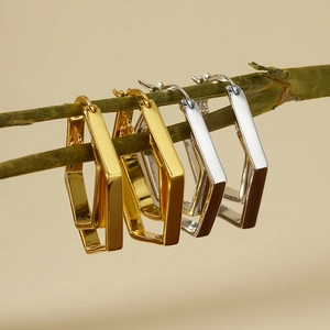 Geometric hexagon double-hoop earrings in polished gold and silver finish hanging on stems
