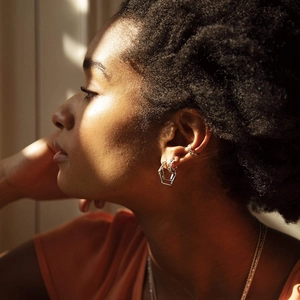 Geometric silver double hoop earrings and ear cuff on a model in natural sunlight