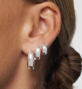 Macro detail of three different sized polished S925 sterling silver hoop earrings on ear
