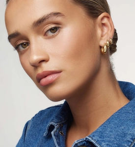 Detail view of a set of three polished gold hoop earrings in graduated sizes on ear