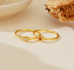 Detailed view of two gold S925 silver rings with red and clear heart-shaped crystals