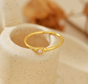 Macro shot of gold heart ring featuring a central sparkling cubic zirconia on ceramic base