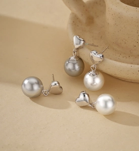 Detail of S925 silver heart stud earrings with white and grey pearls in elegant setting
