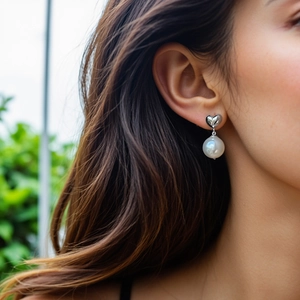Close-up of S925 silver heart stud earrings with elegant white round pearls on model