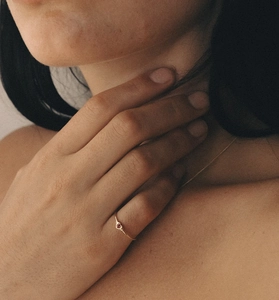 Close-up of minimalist gold ring with heart-shaped red gemstone on model hand