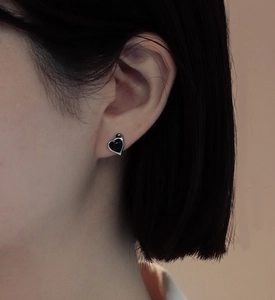 Close-up of S925 sterling silver heart earrings with black agate worn by a model