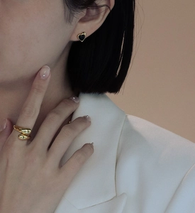 Close-up of elegant gold heart earring with black onyx inlay worn by a model