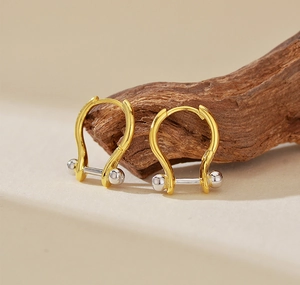 Macro-opname van tweekleurige S925 zilveren U-vormige creolen met goud en zilver finish