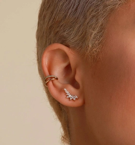 Gros plan sur un earcuff doré et boucles d'oreilles ailes en pierres marquises
