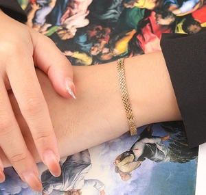Detail of a 6mm gold braided mesh chain bracelet showcasing fine weaving and metallic luster