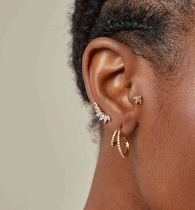 Gros plan de boucles d'oreilles ailes dorées et d'un ear cuff avec oxydes de zirconium