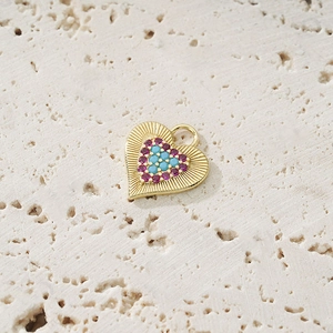 Golden heart pendant with colorful zircon stones on a rustic travertine background
