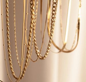 Gros plan détaillé de divers styles de colliers dorés incluant maille corde et box chain