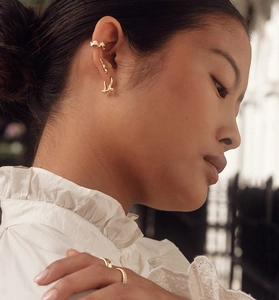 Detailopname van een model met minimalistische gouden oorbellen en verfijnde ringen