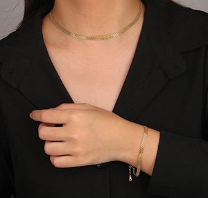 Detailed view of the gold mesh woven bracelet and necklace set on a female model