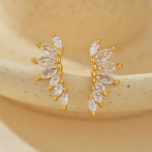 Boucles d'oreilles ailes dorées avec cristaux marquise sur un rebord en céramique