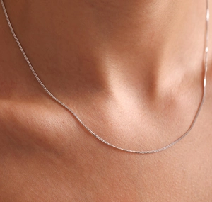 Gros plan d'un collier chaîne fine en argent sterling S925 porté par un mannequin femme