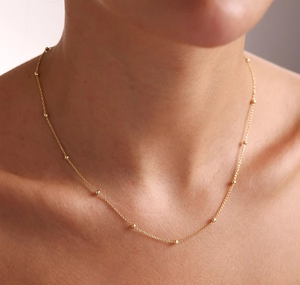 Détail d'un élégant collier ras du cou perlé plaqué or 18 carats sur un cou féminin