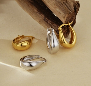 Detail showing S925 hallmark on polished gold and silver teardrop hoop earrings