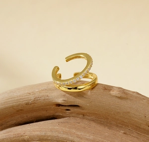 Détail du bijou d'oreille double couche doré avec pierres de zircon blanc sur bois