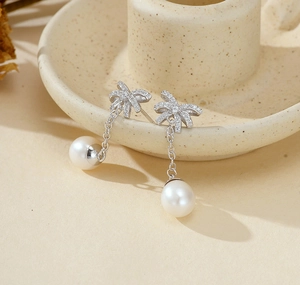 Dettaglio di orecchini a fiocco in argento S925 con zirconi e pendenti di perle