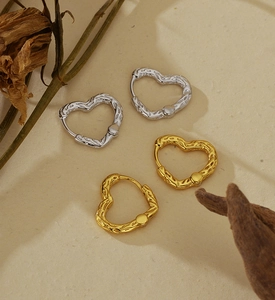 Gros plan de boucles d'oreilles cœur en argent 925 à texture irrégulière dorée et argentée